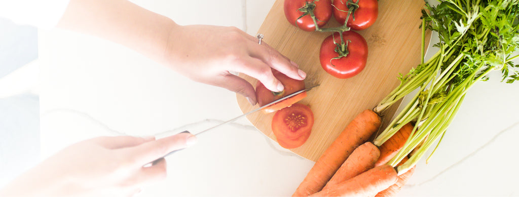 Hands chopping tomatoes and carrots